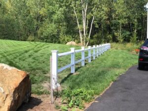 White fence beside driveway and green lawn.
