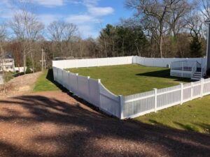 White fenced yard with green grass.
