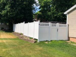 White fence beside house and green lawn.