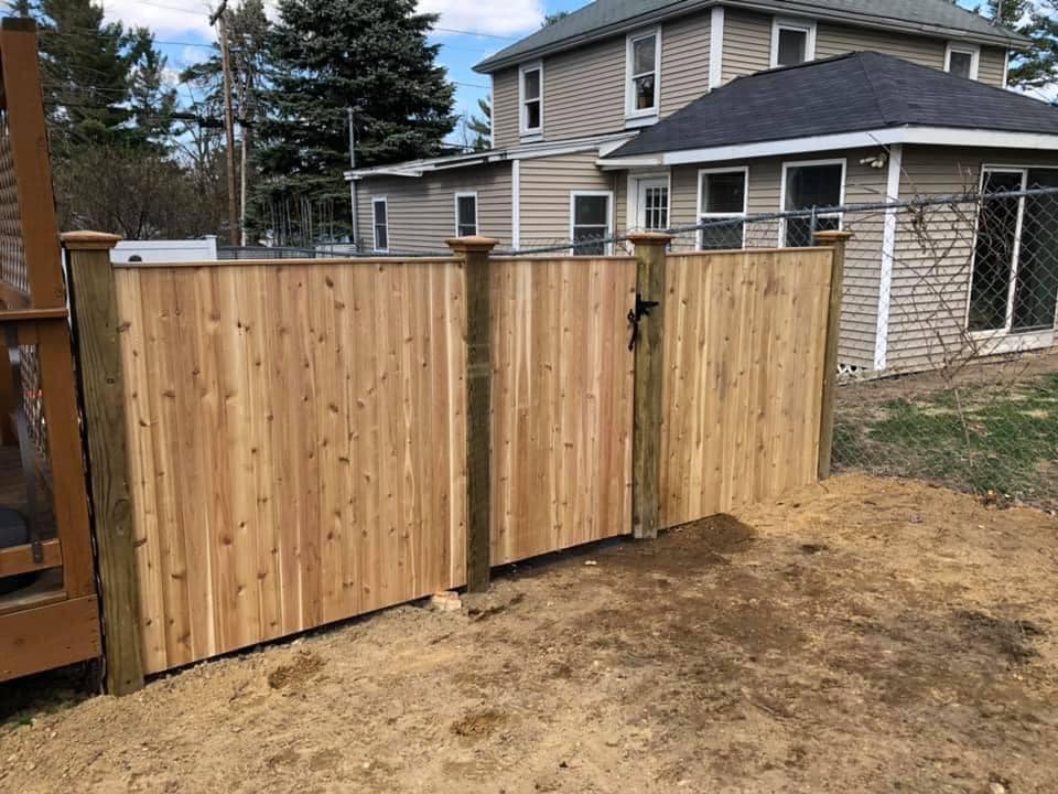 152435679_362113214961078_3327268258836560469_n Wooden fence in front of suburban house.