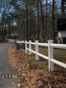 White fence along rural road with mailbox.