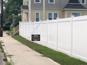 White fence beside sidewalk near residential house.