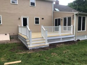 Wooden deck with white railing and steps.