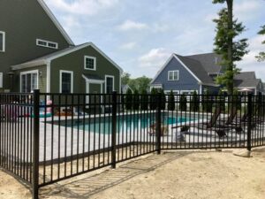 Fenced backyard pool with lounge chairs.