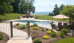 A pool with an outdoor fireplace and patio furniture.